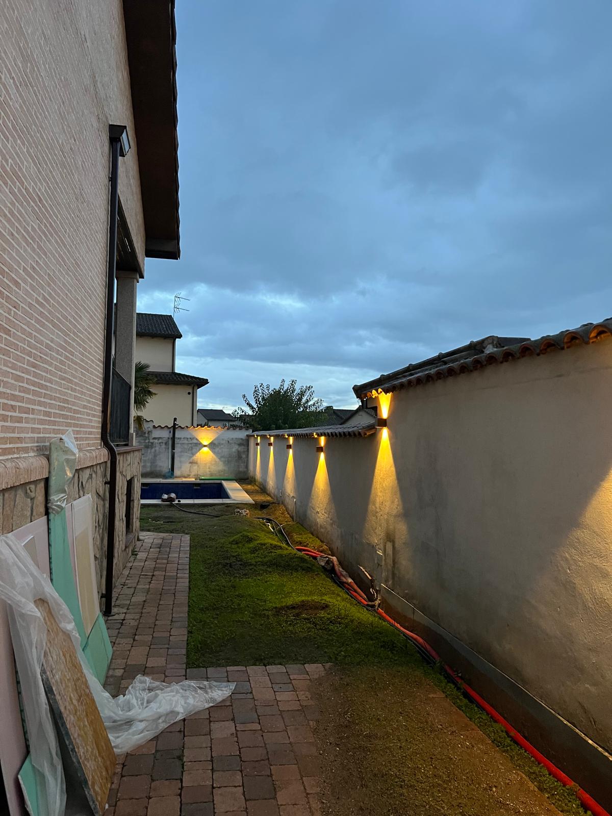 Jardín con apliques de pared iluminados en exterior
