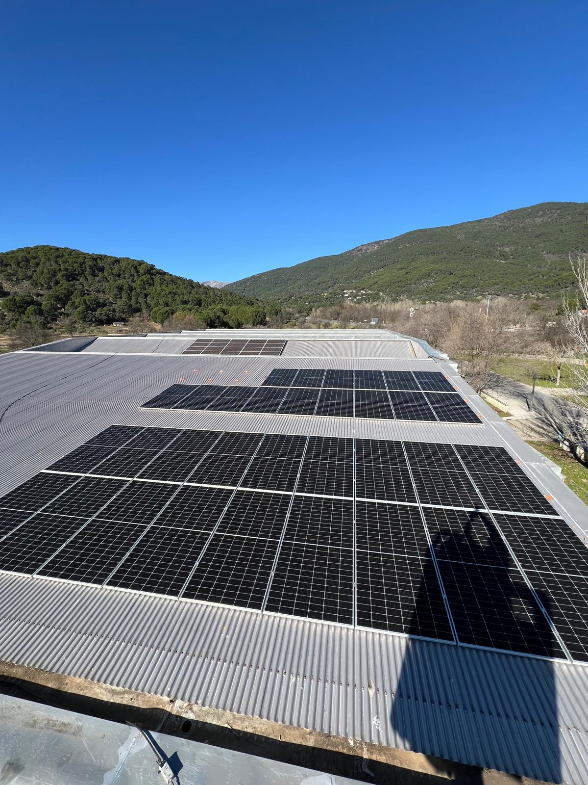 Placas solares en nave industrial con montañas al fondo